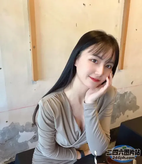 阿拉菲德女人坐在桌子旁，桌上放着一台笔记本电脑