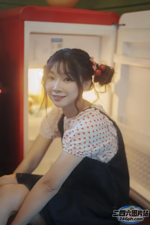 有个女人坐在冰箱前，脸上挂着笑容