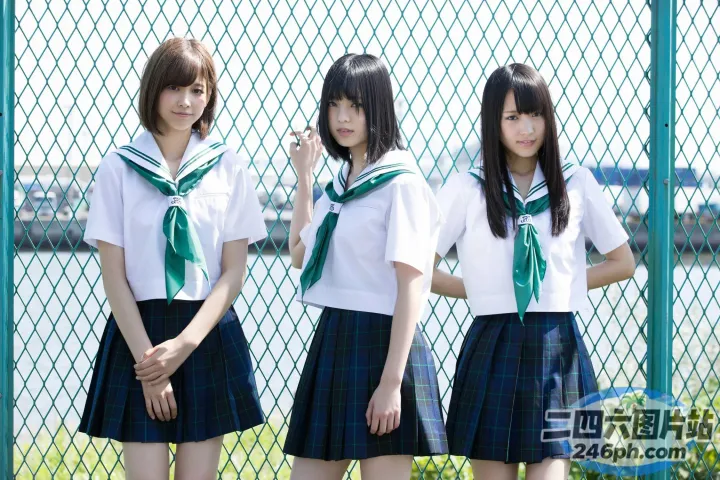 三个穿着校服的女孩站在栅栏旁边