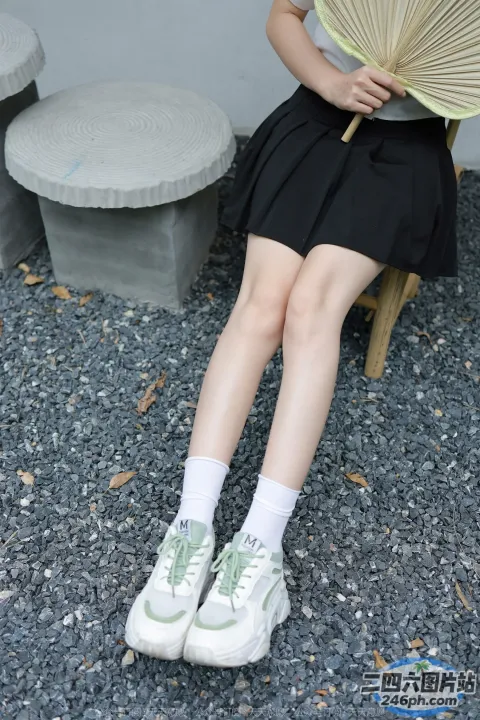 有个女人坐在长凳上，手里拿着一把扇子