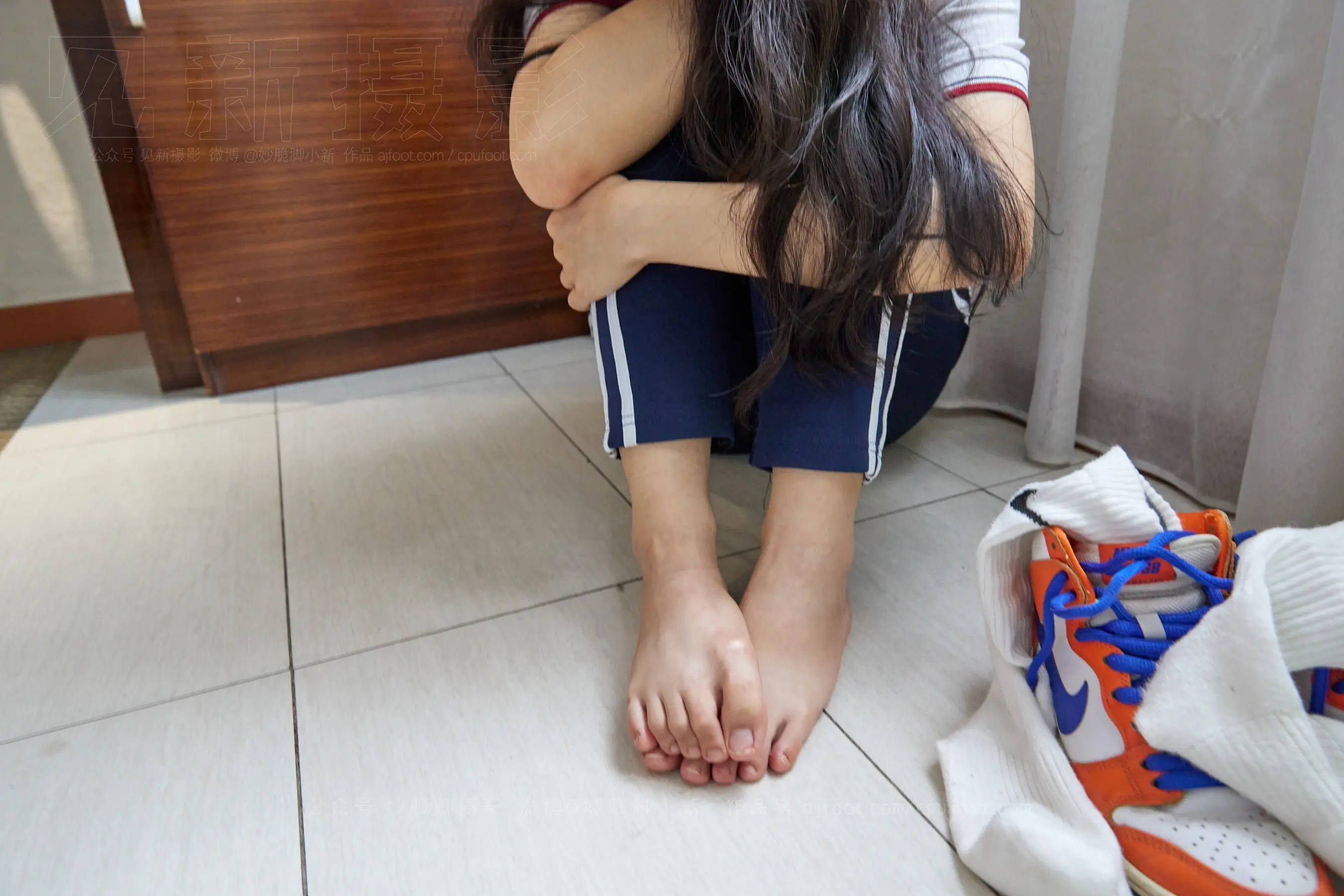有一个女人坐在地板上，双叉