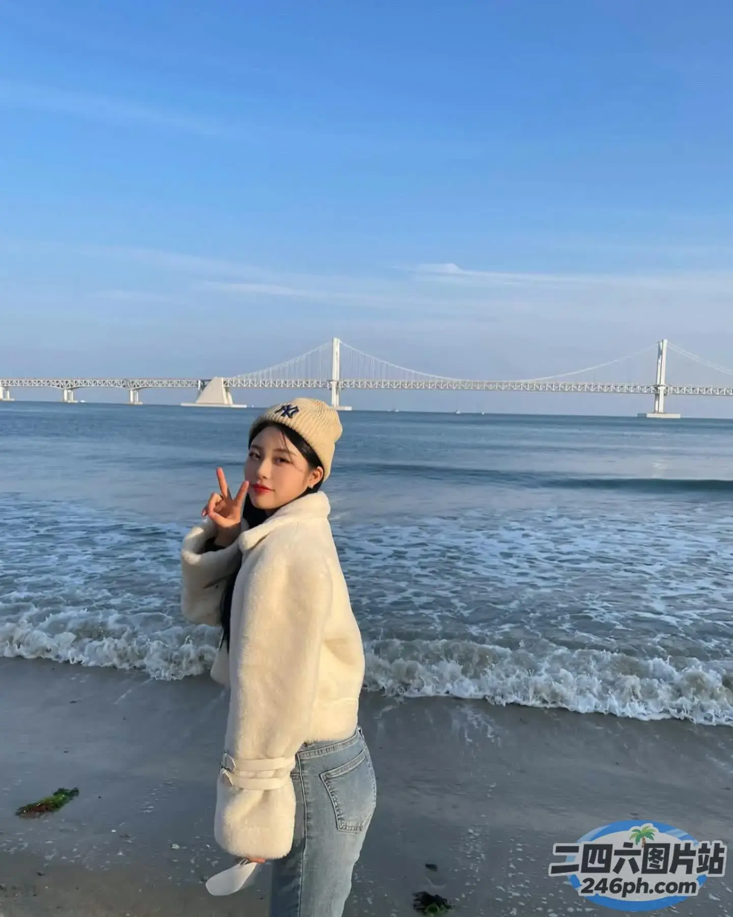站在海滩上的阿拉费德女人，背景是一座桥