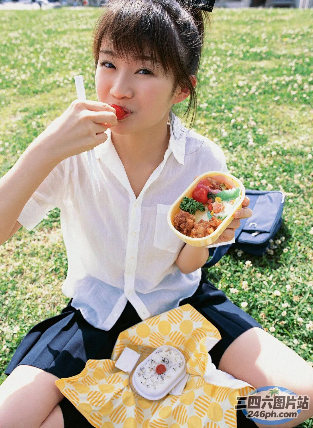 阿拉菲女孩坐在草地上吃热狗