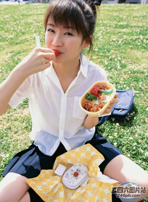 阿拉菲女孩坐在草地上吃热狗
