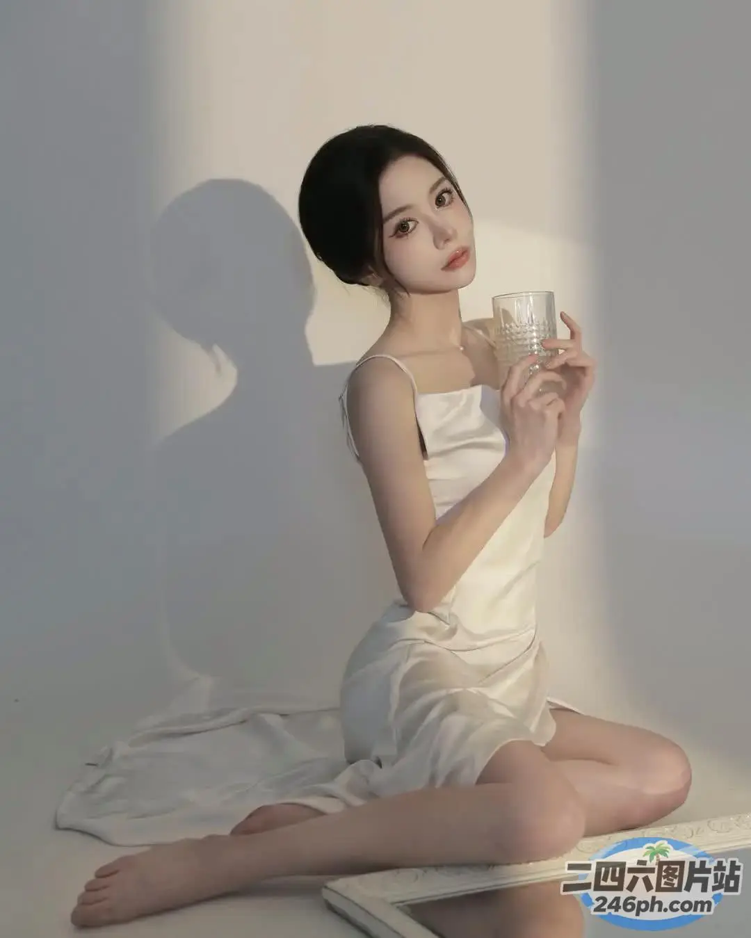 阿拉菲女子坐在地板上，手里拿着一杯水