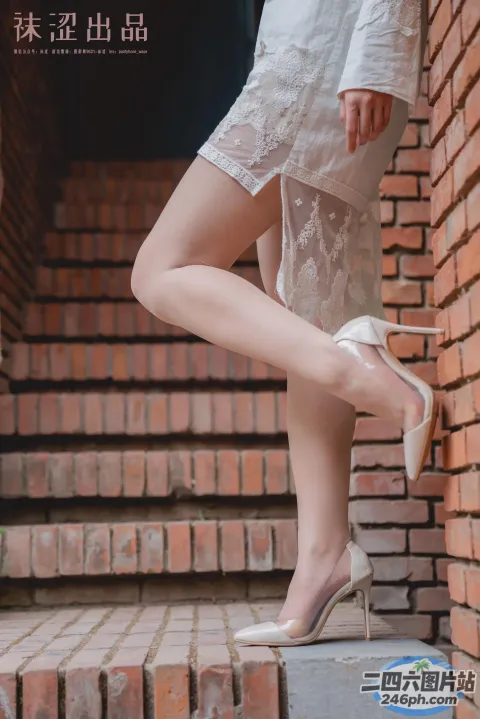 身穿白色连衣裙和高跟鞋的 Araffed 女子站在台阶上