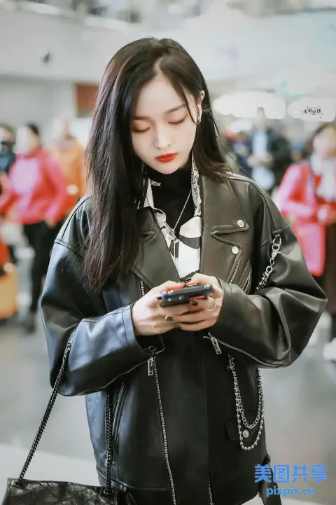 身穿黑色皮夹克的 Araffe 女子正在看手机