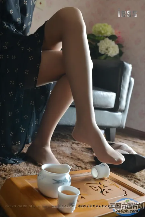 有个女人坐在地毯上，手里拿着一杯茶