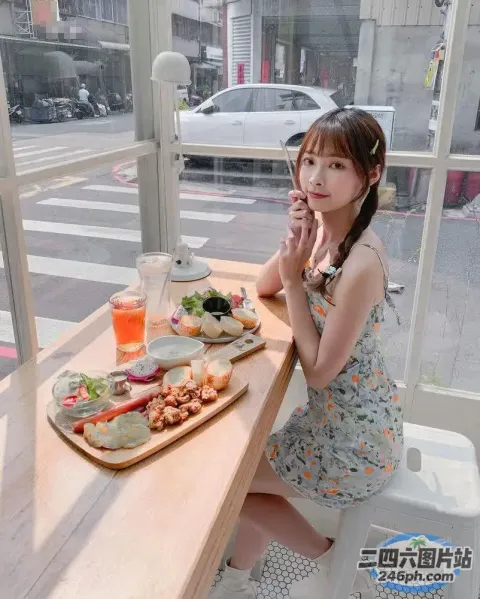 有个女人坐在桌子旁，手里拿着三明治和饮料