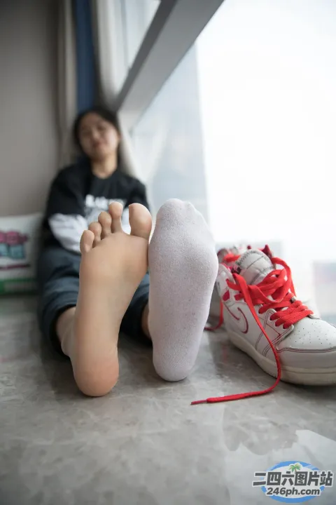 有一个女人坐在地板上，双脚抬起
