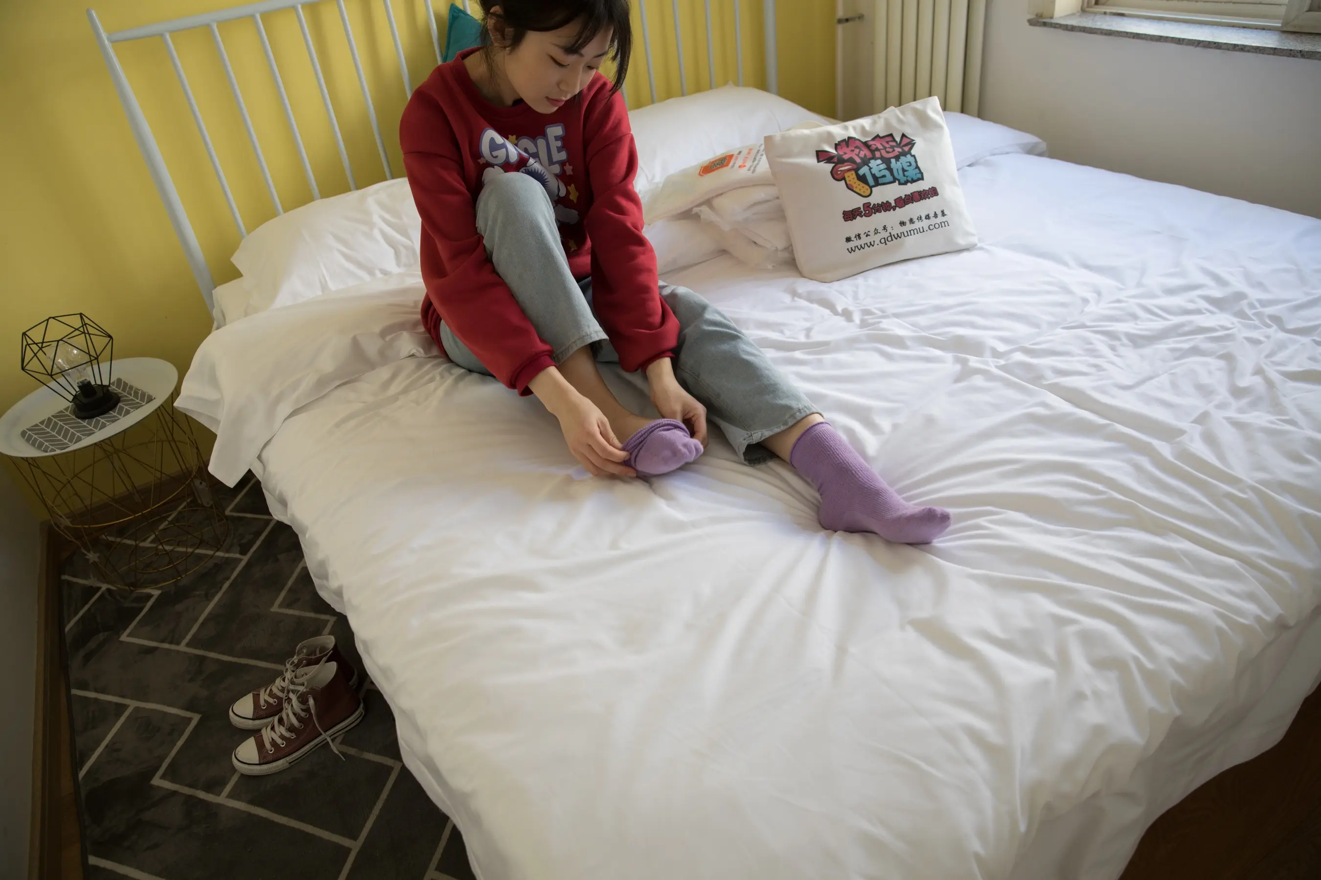 有一个年轻女孩坐在床上，双脚放在床上