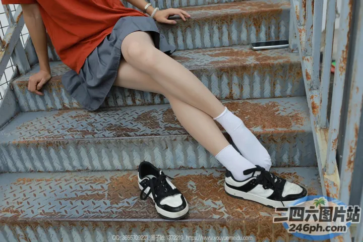 阿拉夫德女人坐在楼梯上，双脚在打电话