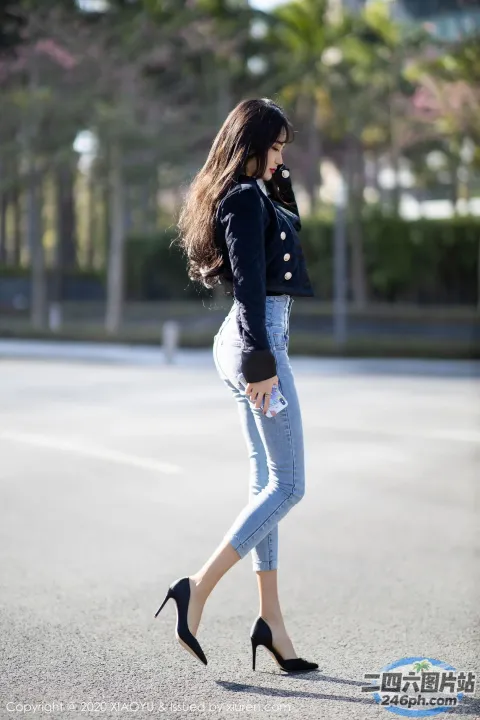 一名穿着高跟鞋的女子走过停车场旁边的街道