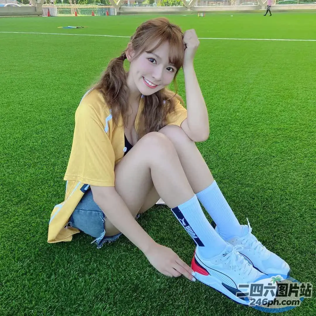 阿拉夫德亚裔妇女坐在草地上，脚踩在足球场上