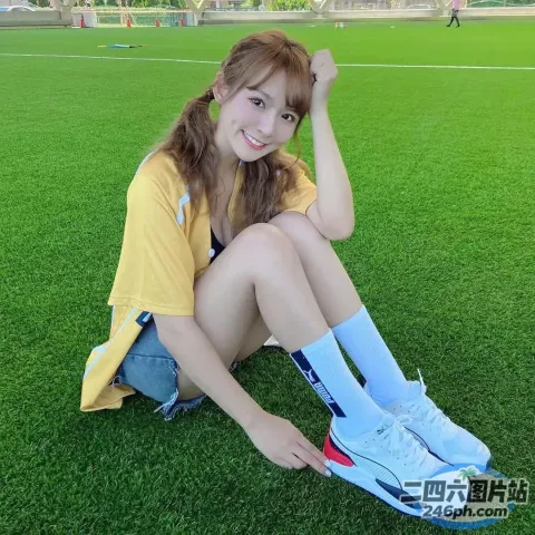 阿拉夫德亚裔妇女坐在草地上，脚踩在足球场上