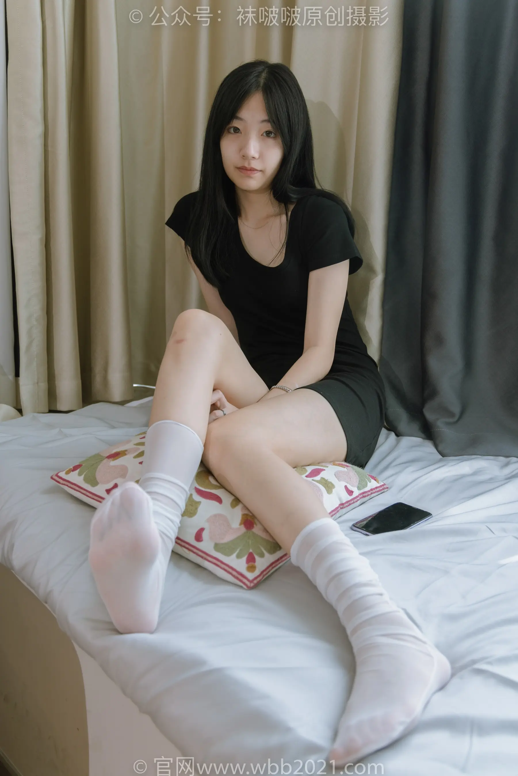 阿拉菲坐在床上，手里拿着一本书和一双袜子