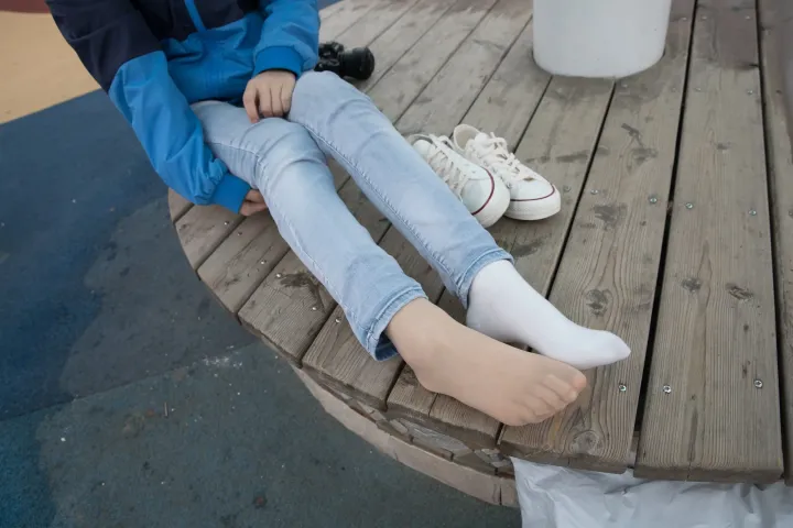 有个女人坐在长凳上，双脚抬起
