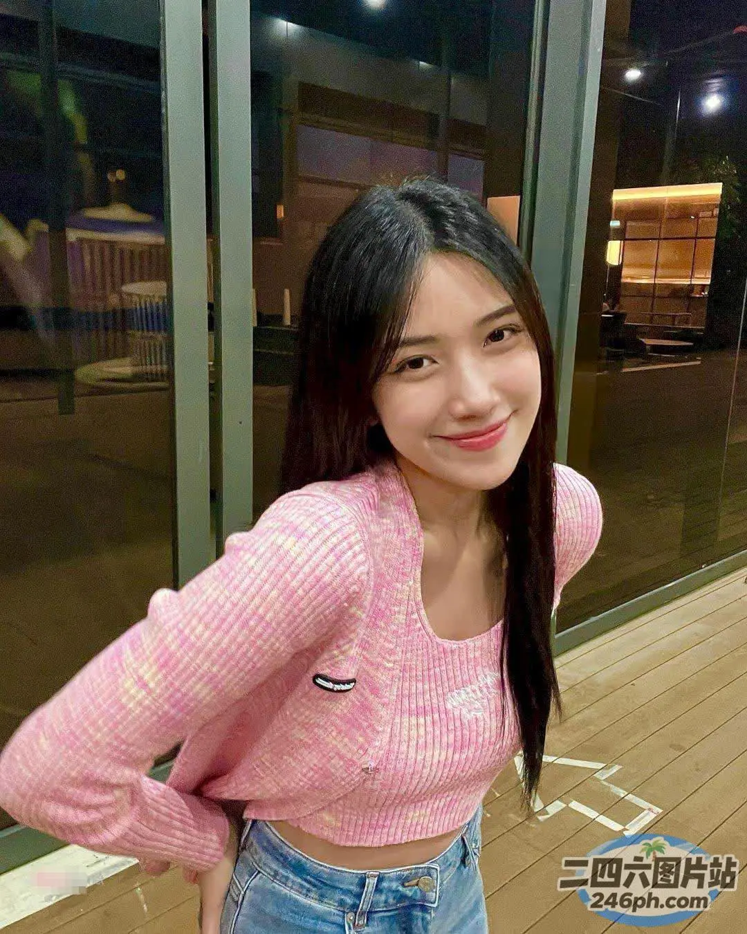 身穿粉红色毛衣和牛仔裤的亚洲女子站在玻璃门前