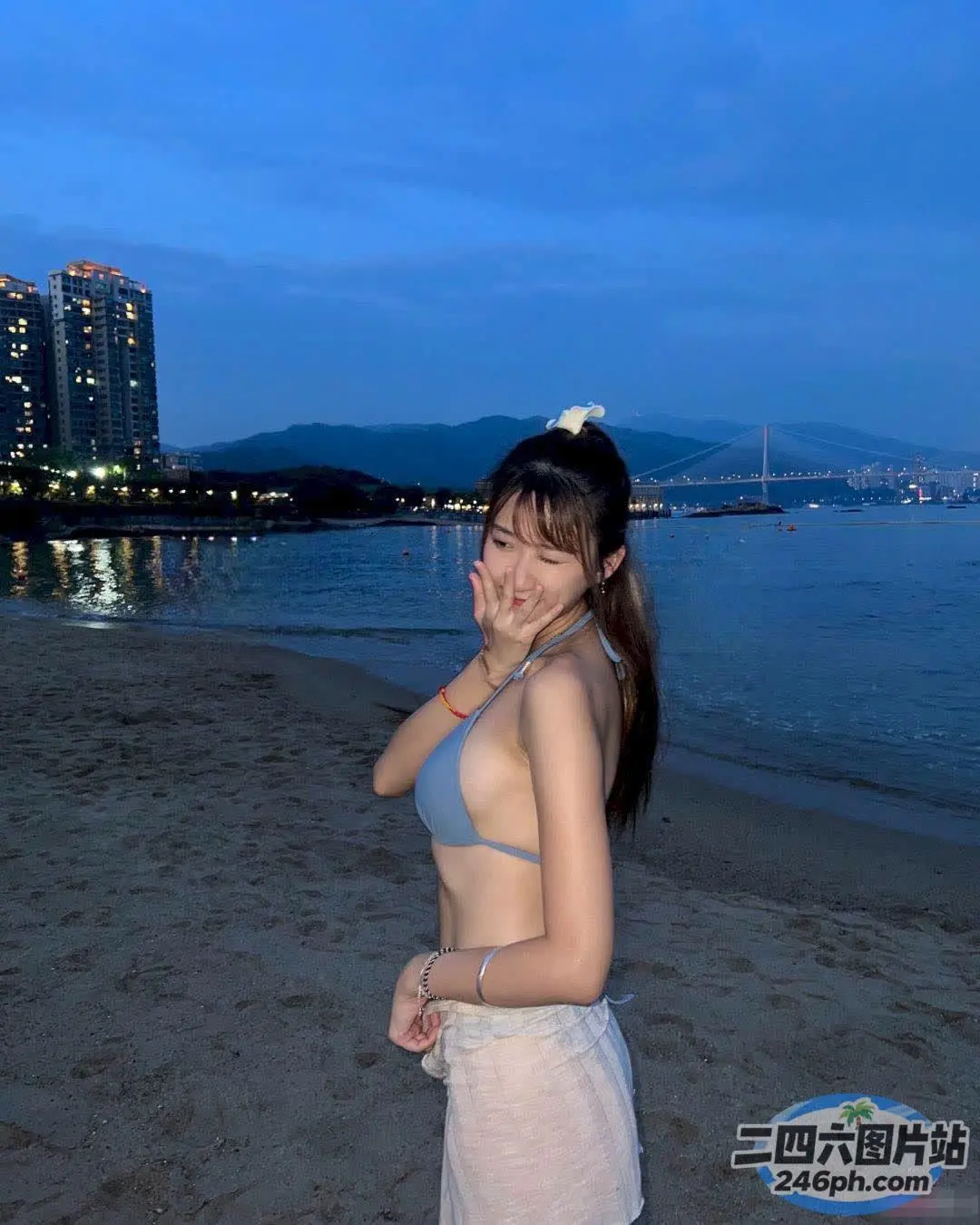 有一个女人站在沙滩上，身上缠着毛巾
