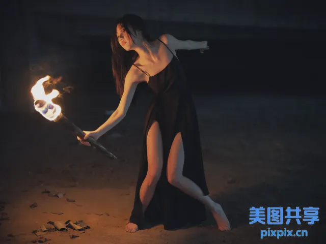 身穿黑色连衣裙的 arafed 女子手持火棍
