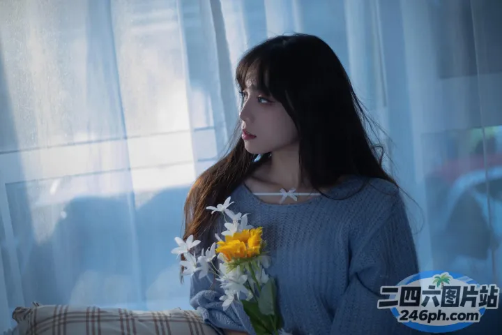 有一位女士坐在沙发上，手里拿着一束鲜花