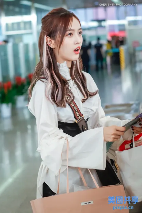 在机场手里拿着包和杂志的女人