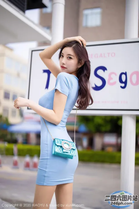 一名身穿蓝色连衣裙的女子在标牌前合影留念
