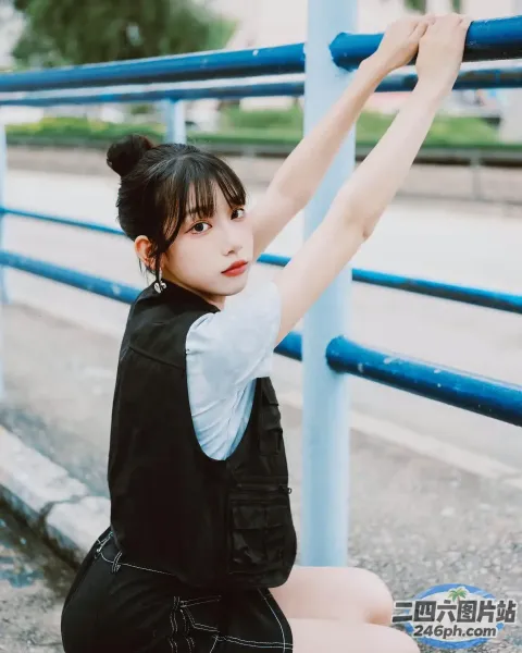 一名女子坐在蓝色栏杆旁的地上