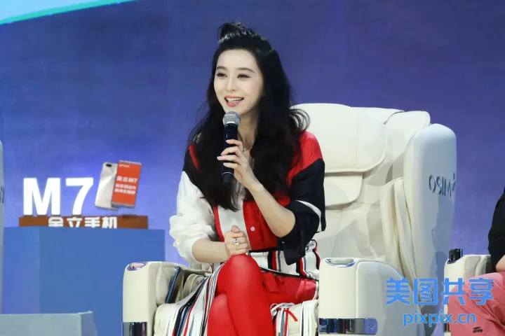 红裙女子坐在椅子上，手里拿着麦克风