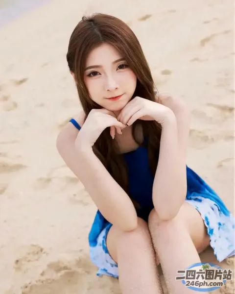 一个女人坐在海滩上，双手放在下巴上的特写