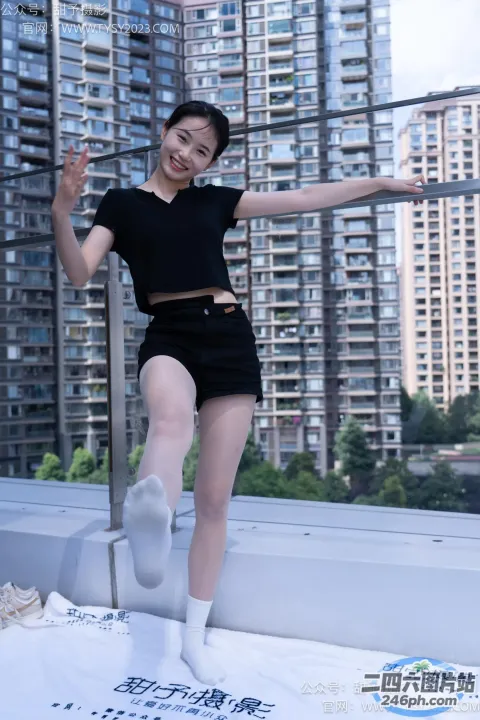 身穿黑色连衣裙的 Arafed 女子在屋顶上摆姿势，背景是建筑物