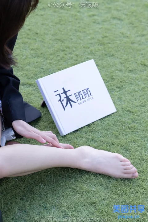有个女人坐在草地上，手里拿着一本书