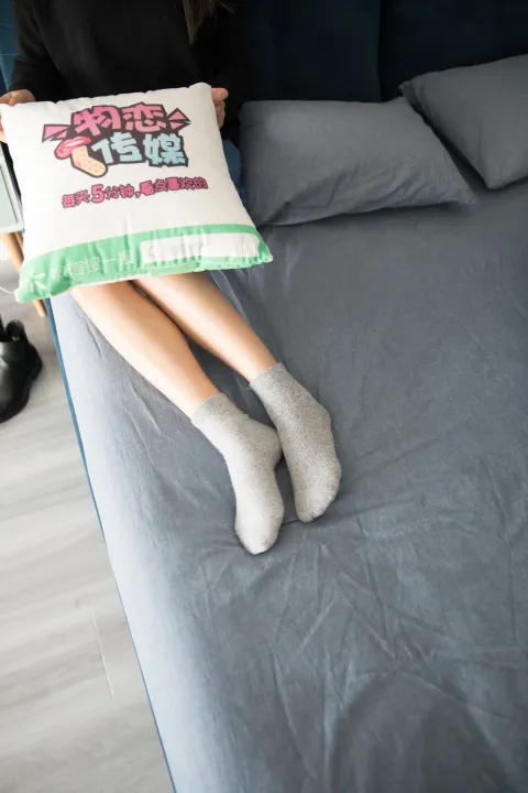坐在床上的女人，手里拿着一个枕头，上面有一个枕套