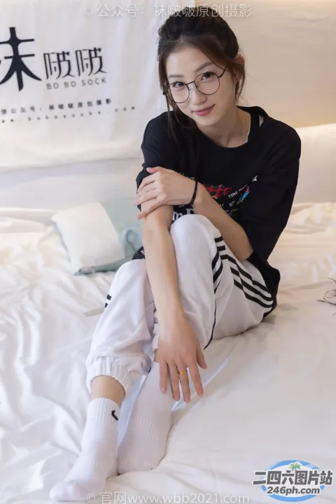 坐在床上的阿拉夫德女人，穿着黑色衬衫和白色裤子