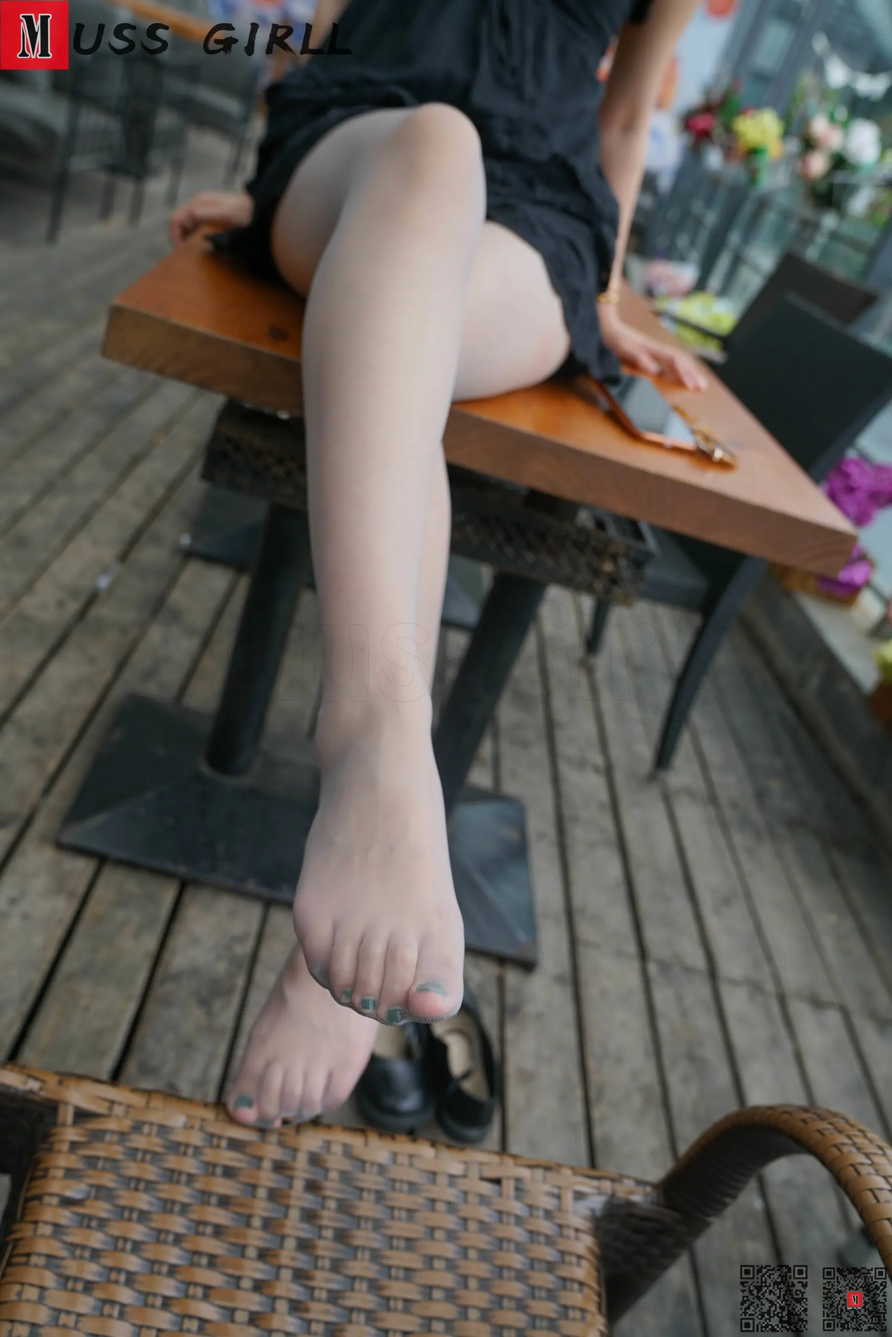 有一个女人坐在桌子上，她的脚放在桌子上