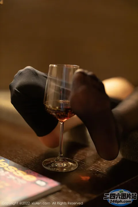 有人在桌子上拿着一个酒杯，桌上放着一本书