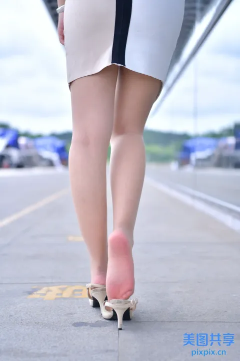 有一个女人穿着鞋子走在人行道上