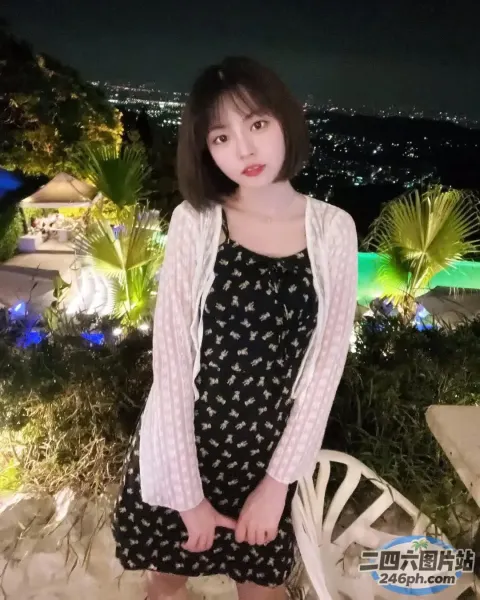 身穿黑色连衣裙和白色开衫的 araffe 女子站在泳池前