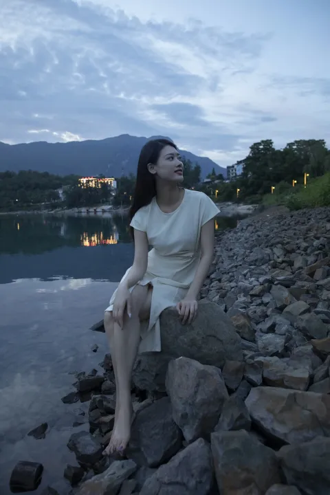 黄昏时分坐在水边岩石上的阿拉夫德女人