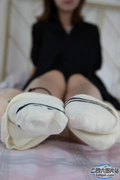 穿着黑色连衣裙的阿拉夫德女人坐在床上，穿着白色袜子