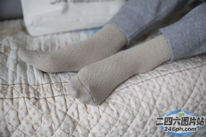有人躺在床上，手里拿着一双袜子
