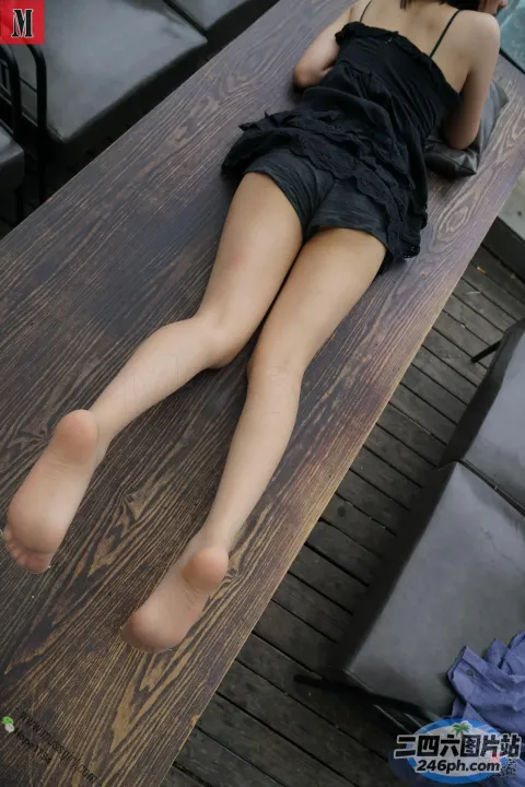 有一个女人躺在桌子上，双腿交叉