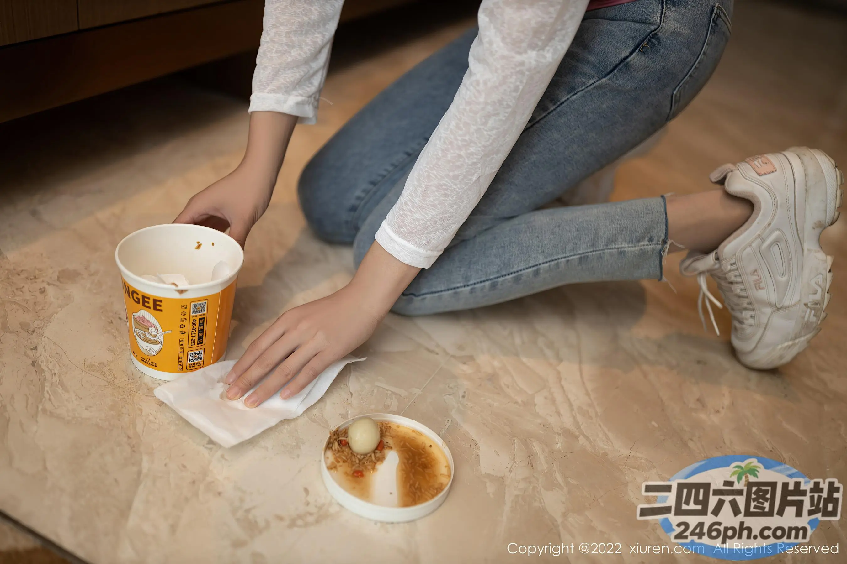 有人坐在地板上，拿着一杯咖啡和一张餐巾纸
