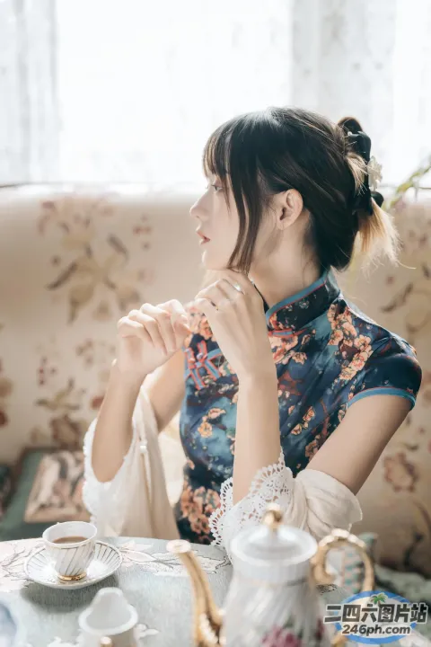 有一位女士坐在一张桌子旁，桌上放着茶壶和茶杯