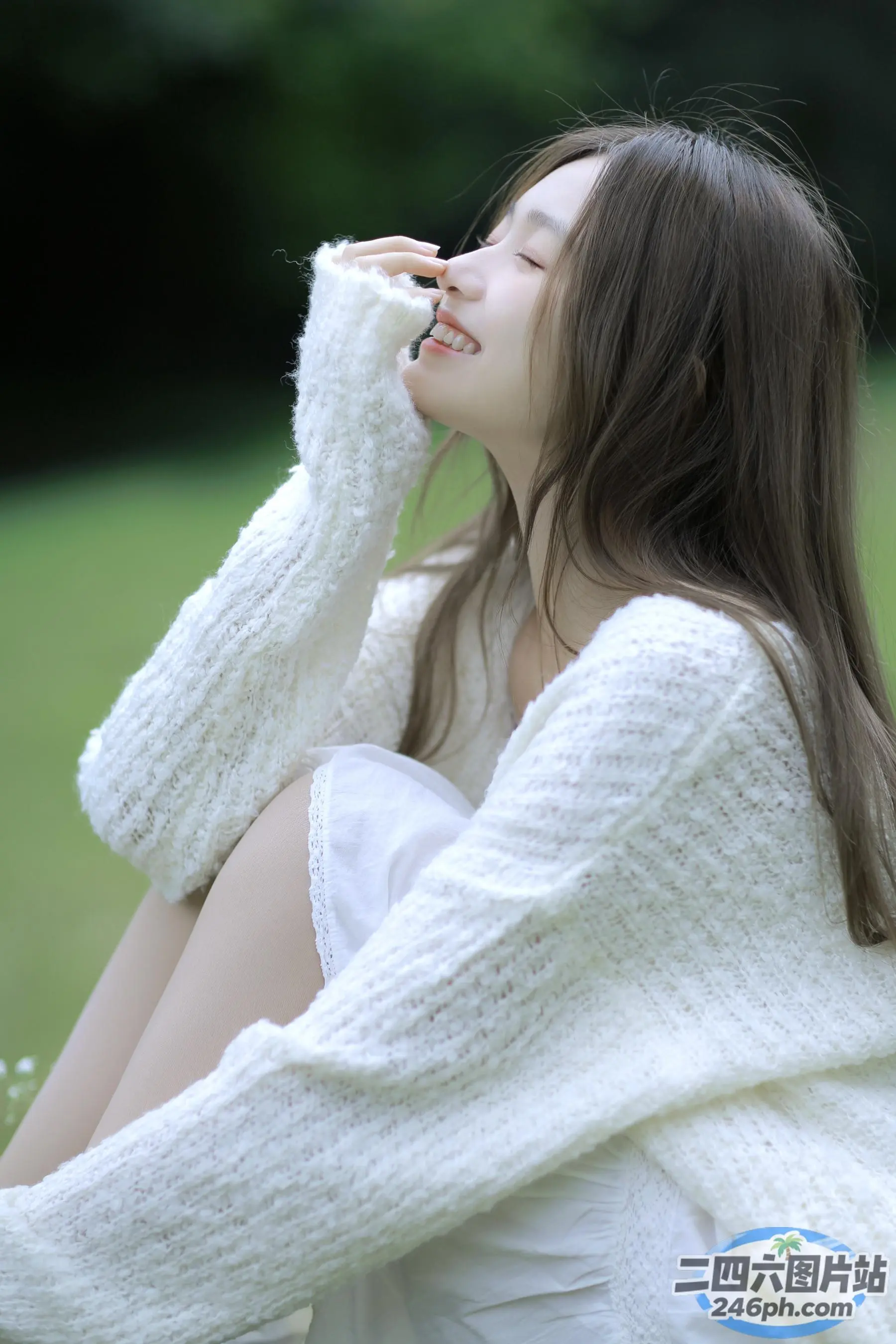 阿拉菲女人坐在草地上，闭着眼睛，手捂着脸