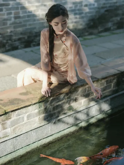 阿拉菲女人坐在窗台上看着池塘里的鱼