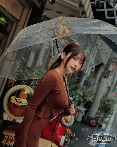 身穿棕色连衣裙的女子在城市街道上撑着伞