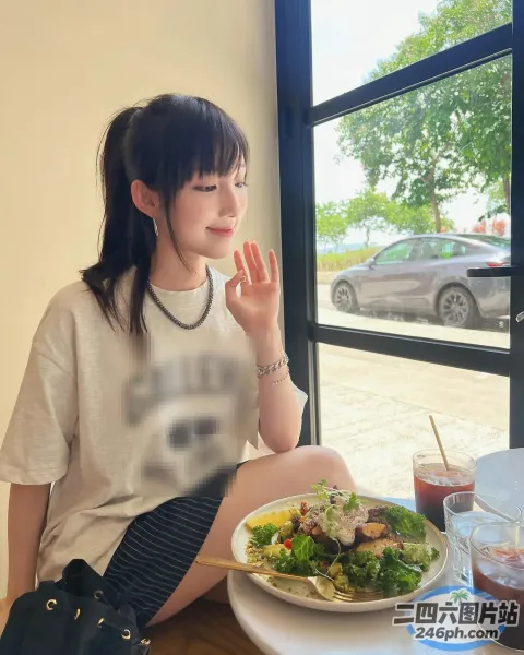 阿拉菲坐在一张桌子旁，桌上放着一盘食物和一杯饮料