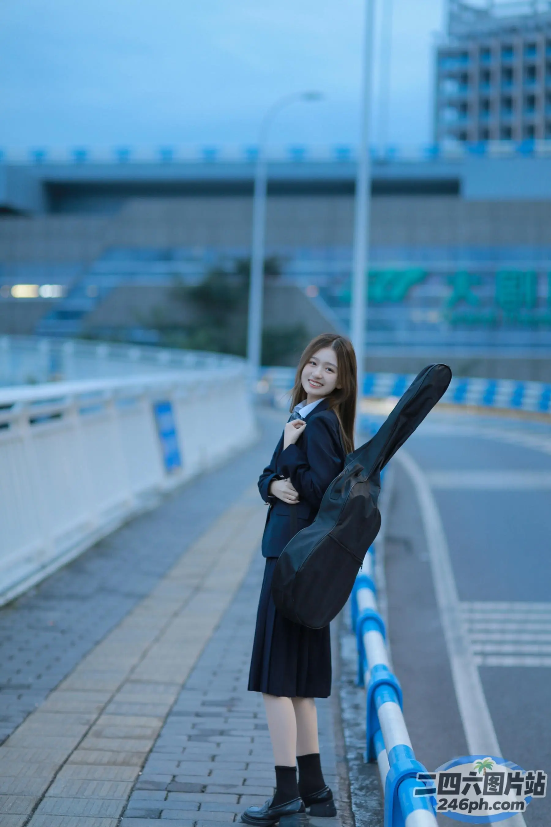 人行道上站着一个年轻女孩，手里拿着一个吉他盒