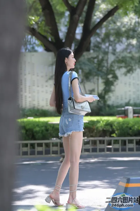 穿着牛仔短裤和背包的 araffe 女人走在街上
